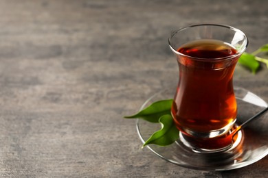 Photo of Glass with traditional Turkish tea on grey table, space for text