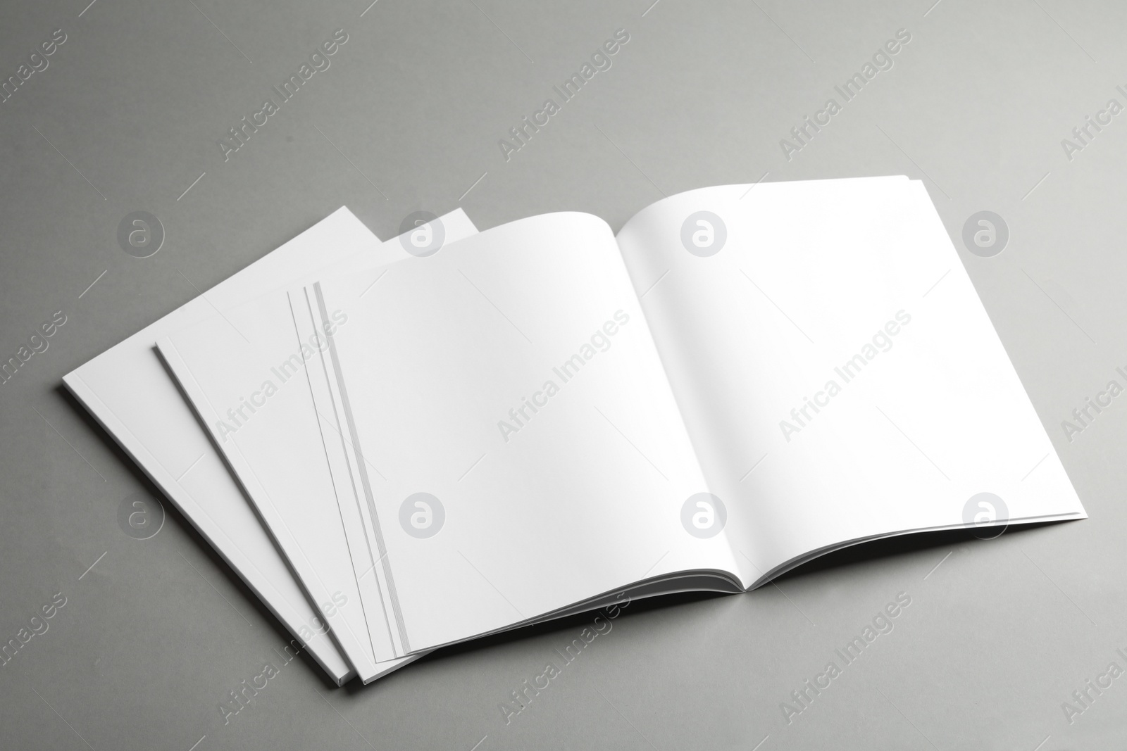 Photo of Open and closed blank brochures on grey background. Mock up for design