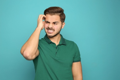 Photo of Young man scratching head on color background. Annoying itch