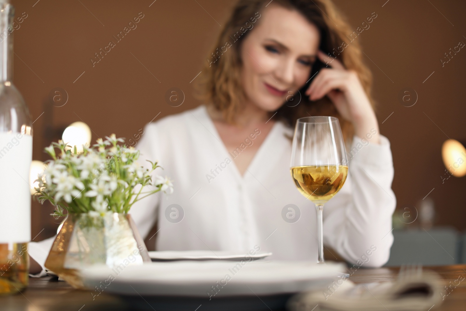 Photo of Woman with glass of wine at table in restaurant