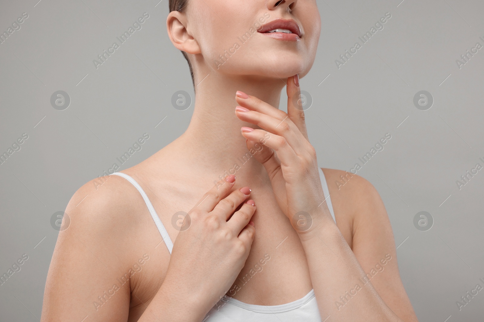 Photo of Woman touching her chin on grey background, closeup