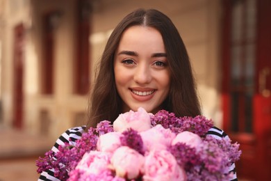 Beautiful woman with bouquet of spring flowers outdoors