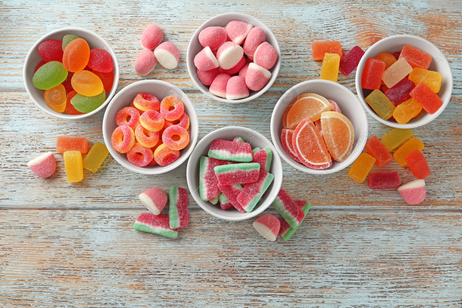 Photo of Flat lay composition with bowls of different jelly candies on wooden background