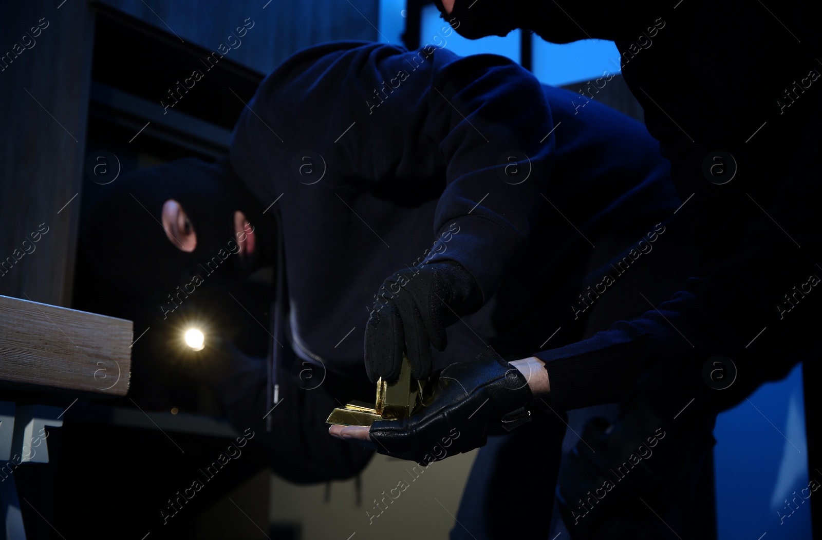 Photo of Thieves taking gold bars out of steel safe indoors at night