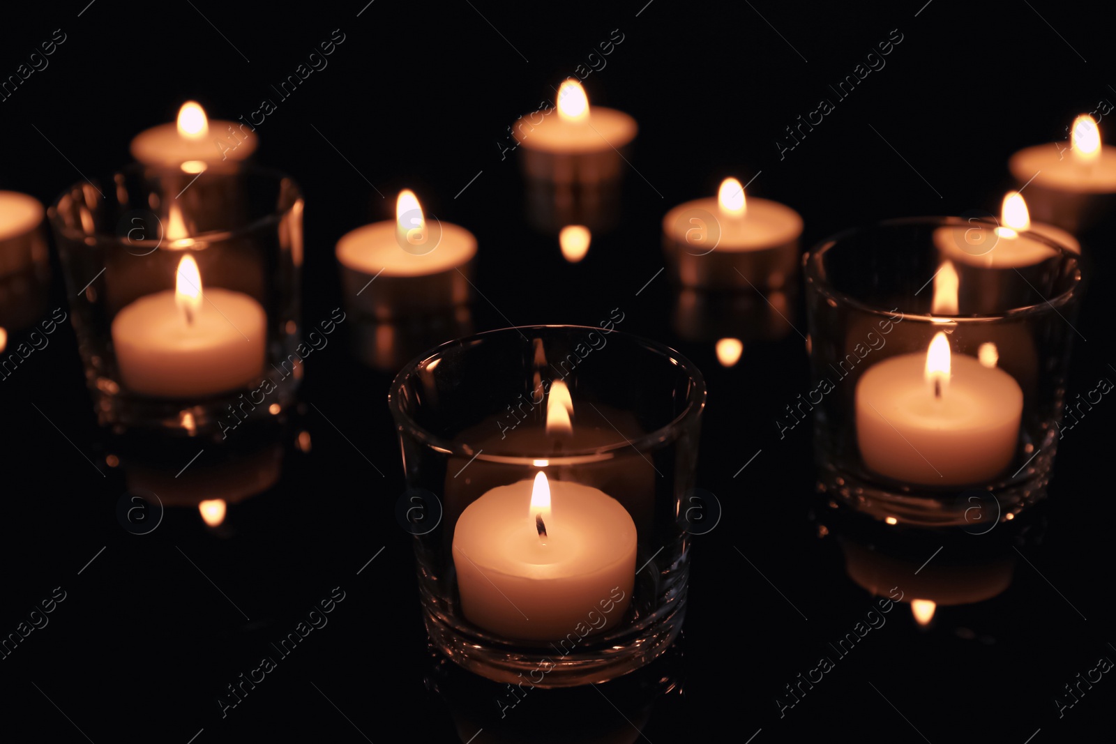 Photo of Burning candles in glass holders on dark background