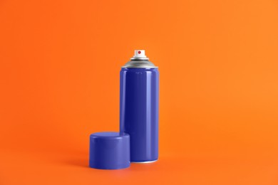 Photo of Blue can of spray paint on orange background. Space for text