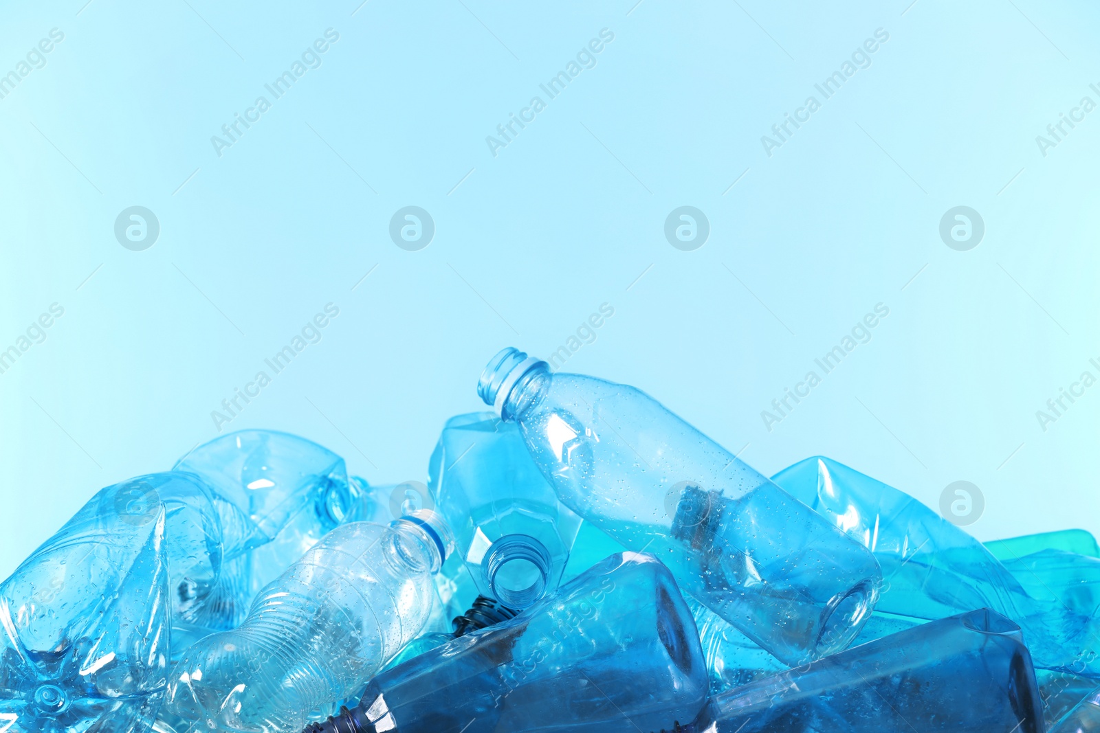 Photo of Pile of used plastic bottles and space for text on color background. Recycling problem