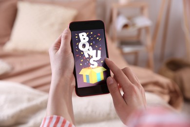Bonus gaining. Woman using smartphone indoors, closeup. Illustration of open gift box, word and confetti on device screen