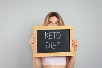 Woman holding blackboard with phrase Keto Diet on grey background