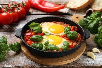Photo of Delicious Shakshuka with basil on wooden table