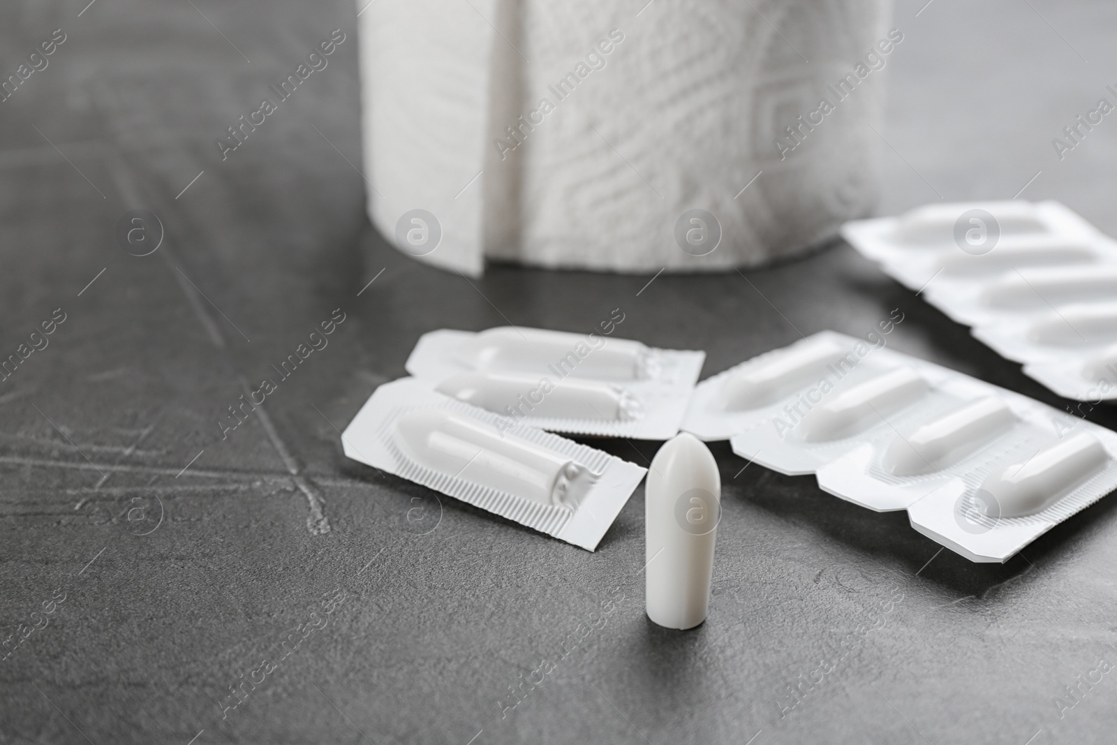 Photo of Suppositories on grey stone table. Hemorrhoid treatment