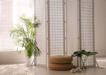 Photo of Stylish room interior with white folding screen and plants