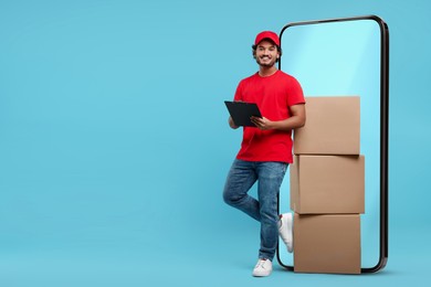 Image of Courier with stack of parcels and clipboard near huge smartphone on light blue background. Delivery service. Space for text