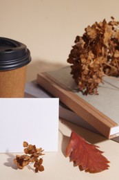 Photo of Dried hortensia flowers, sheet of paper and cardboard cup on beige table. Space for text
