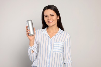 Photo of Beautiful young woman holding tin can with beverage on light grey background