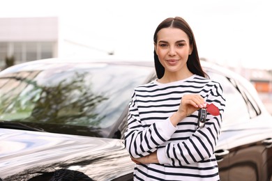 Photo of Woman holding car flip key near her vehicle outdoors