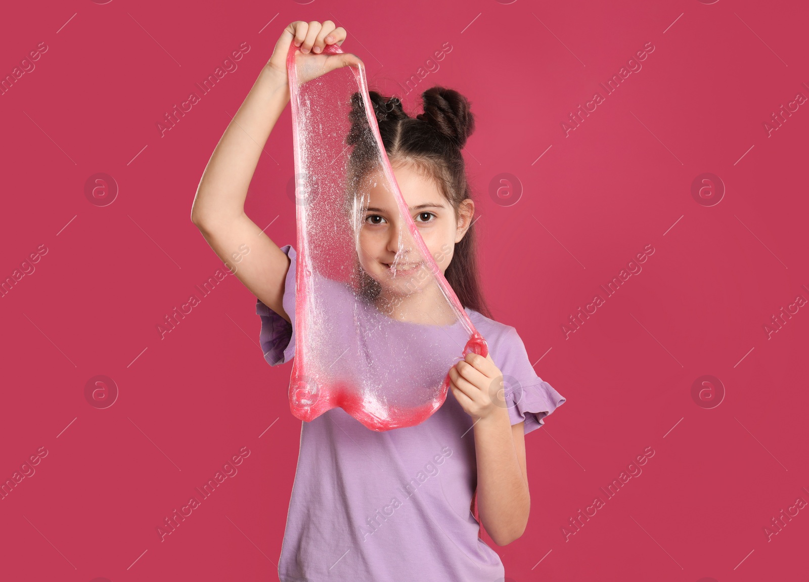 Photo of Little girl with slime on pink background