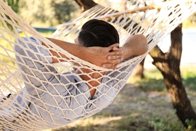 Photo of Man relaxing in hammock outdoors on sunny day. Summer vacation