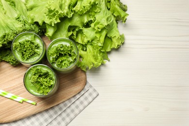 Photo of Green smoothie of lettuce leaves in glasses on white wooden table, flat lay. Space for text
