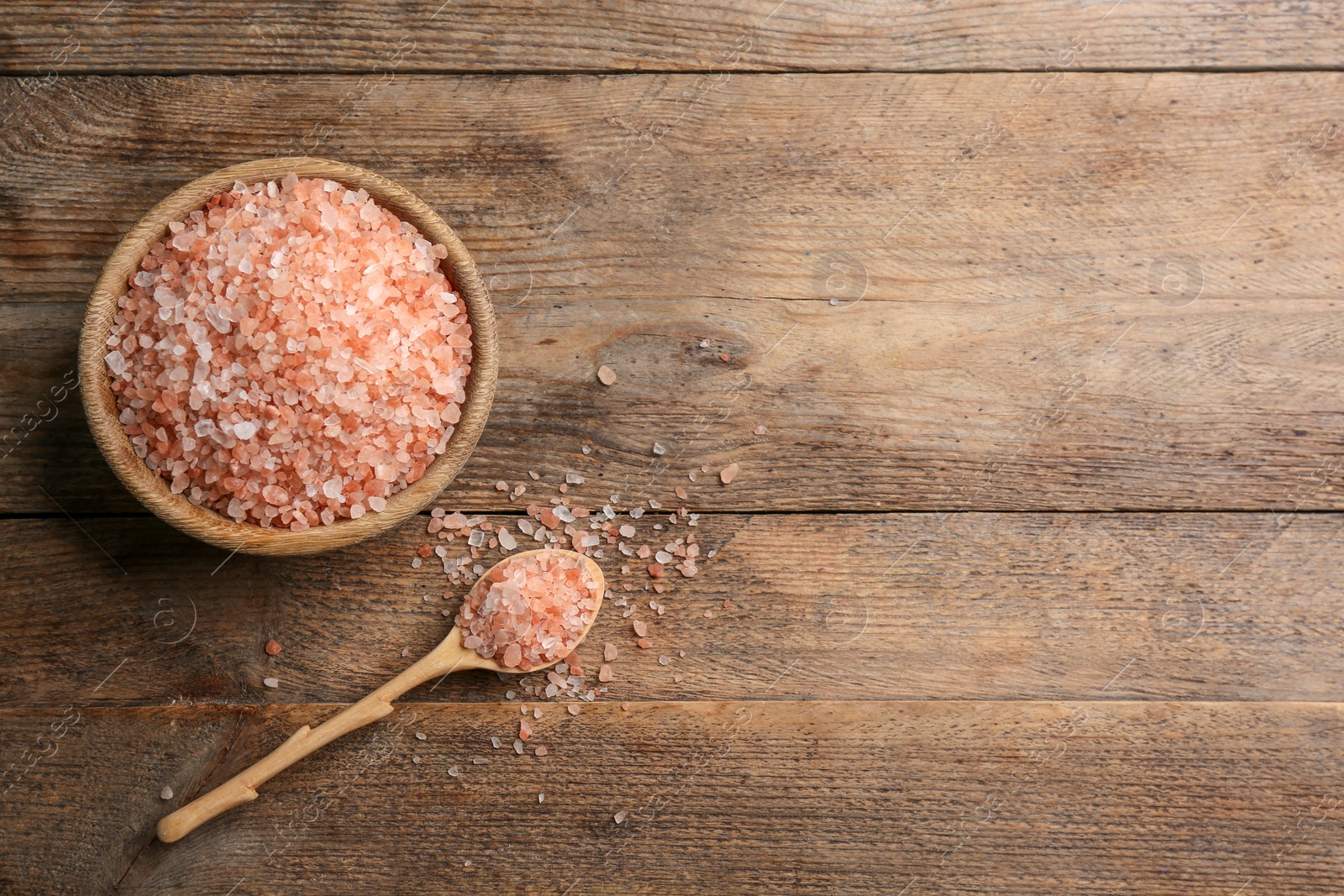 Photo of Pink himalayan salt on wooden table, flat lay. Space for text