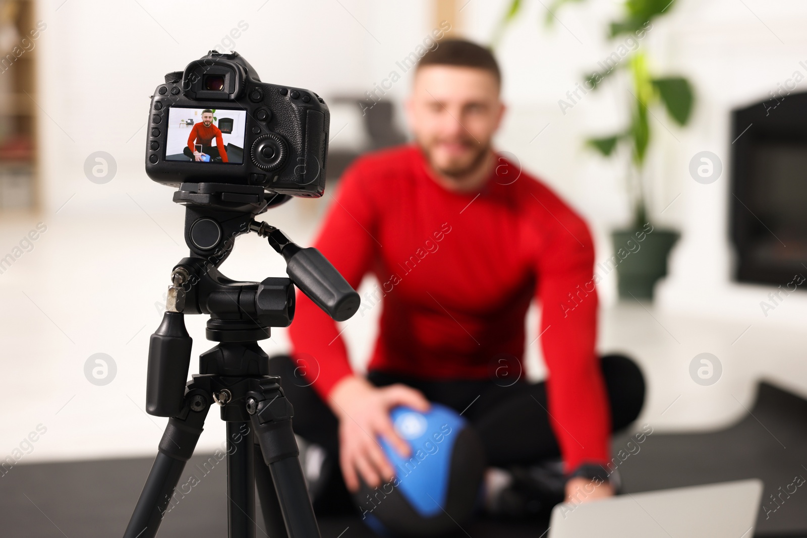 Photo of Trainer recording fitness lesson at home, focus on camera. Space for text