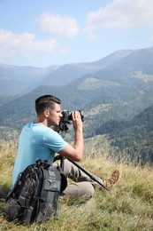 Professional photographer taking picture with modern camera in mountains