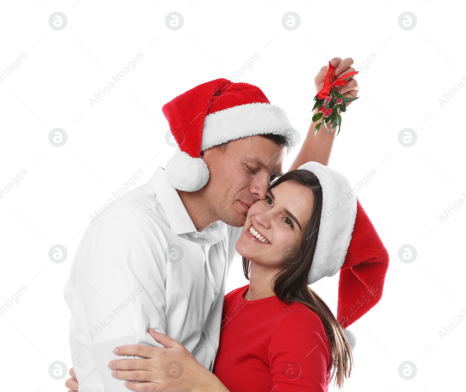 Photo of Happy man kissing his girlfriend under mistletoe bunch on white background