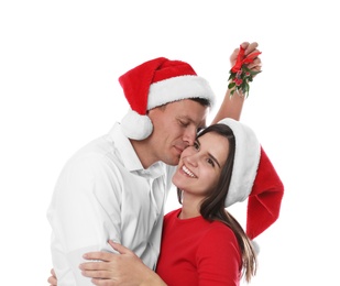 Happy man kissing his girlfriend under mistletoe bunch on white background