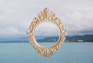 Vintage frame and mountains near sea under cloudy sky