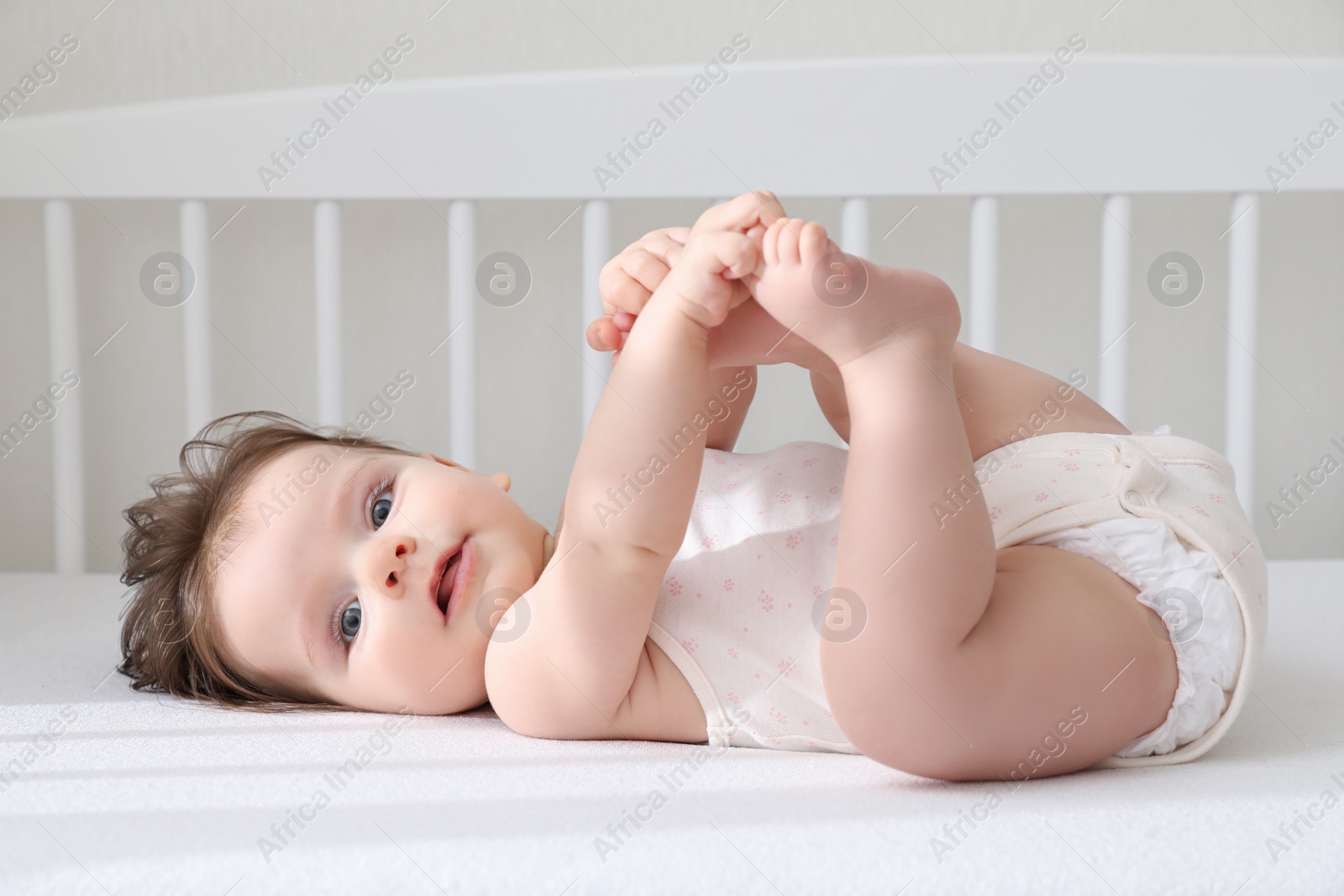 Photo of Cute little baby lying in comfortable crib at home