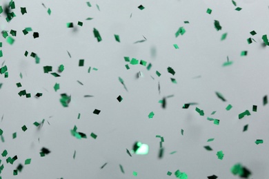 Photo of Shiny green confetti falling down on light grey background