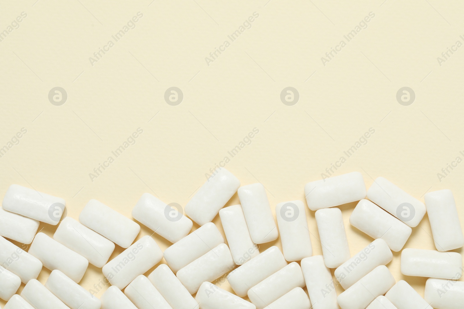 Photo of Tasty white chewing gums on beige background, flat lay. Space for text