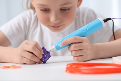 Girl drawing with stylish 3D pen at white table indoors, selective focus