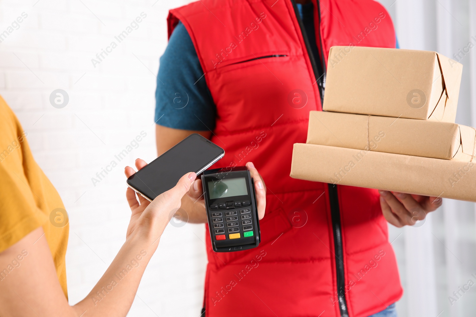 Photo of Young woman with smartphone using terminal for delivery payment indoors, closeup