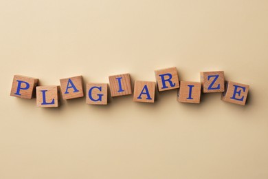 Photo of Wooden cubes with word Plagiarize on beige background, flat lay