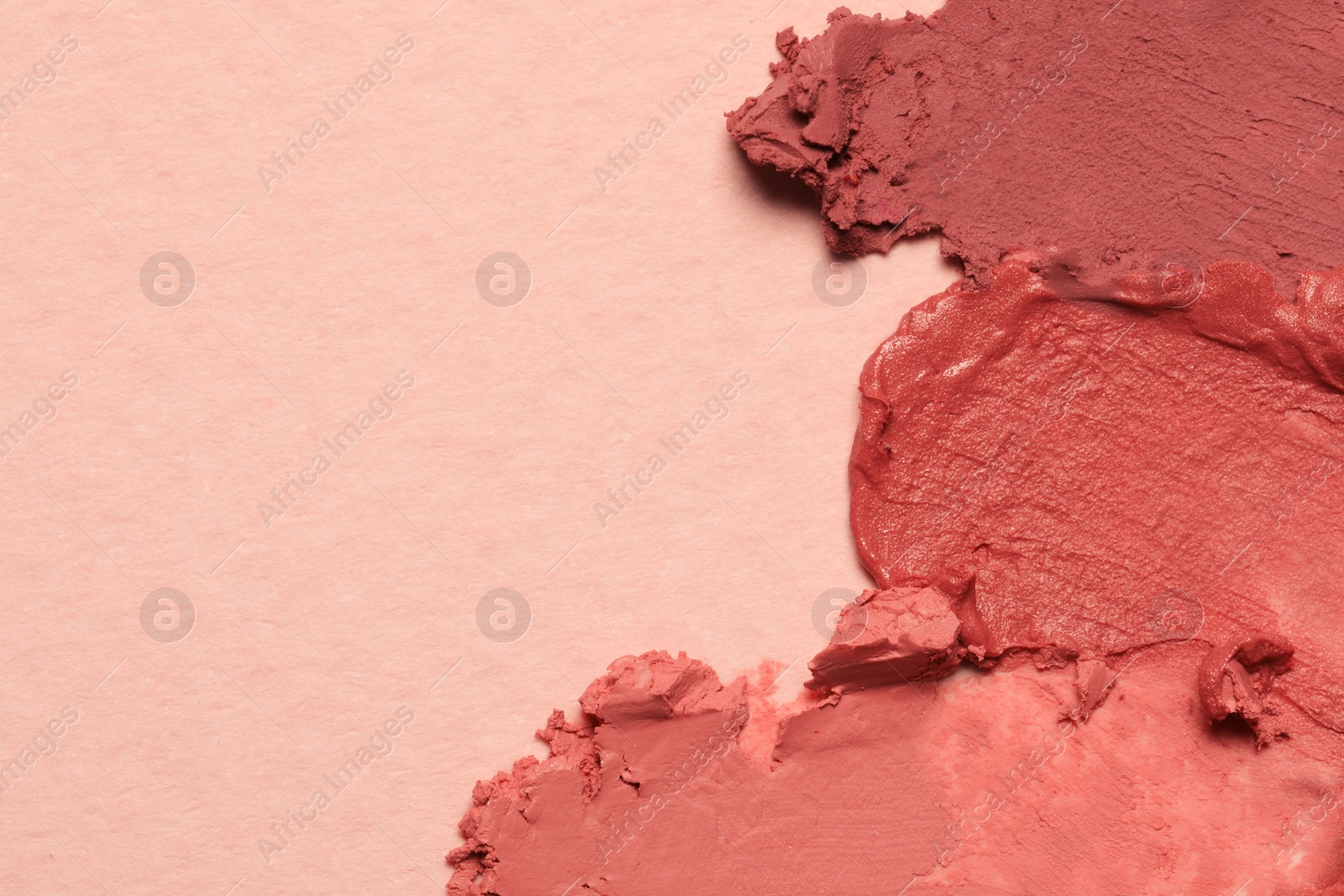 Photo of Smears of beautiful lipsticks on light background, top view. Space for text