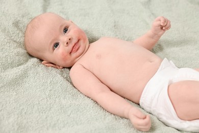 Photo of Cute little baby with allergic redness on cheeks lying on light green blanket