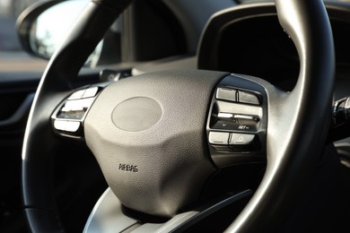 Black steering wheel inside of modern car, closeup