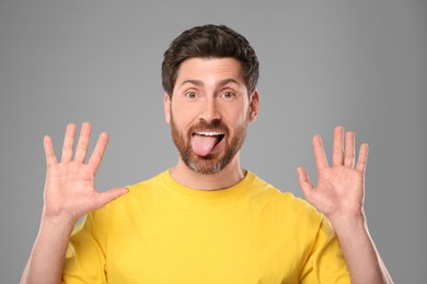 Photo of Man showing his tongue on gray background