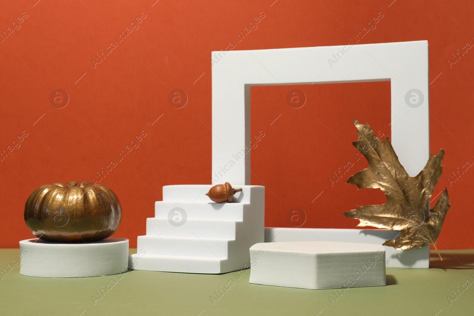 Photo of Autumn presentation for product. Geometric figures, golden leaf, pumpkin and acorn on color background