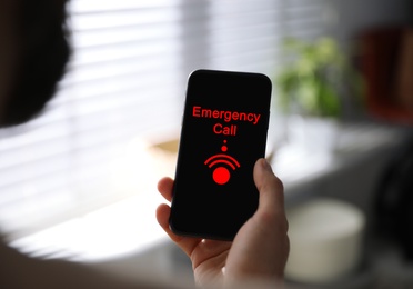 Image of Hotline service. Man making emergency call via smartphone indoors, closeup