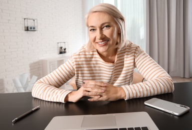 Photo of Mature woman using video chat on laptop at home, view from web camera