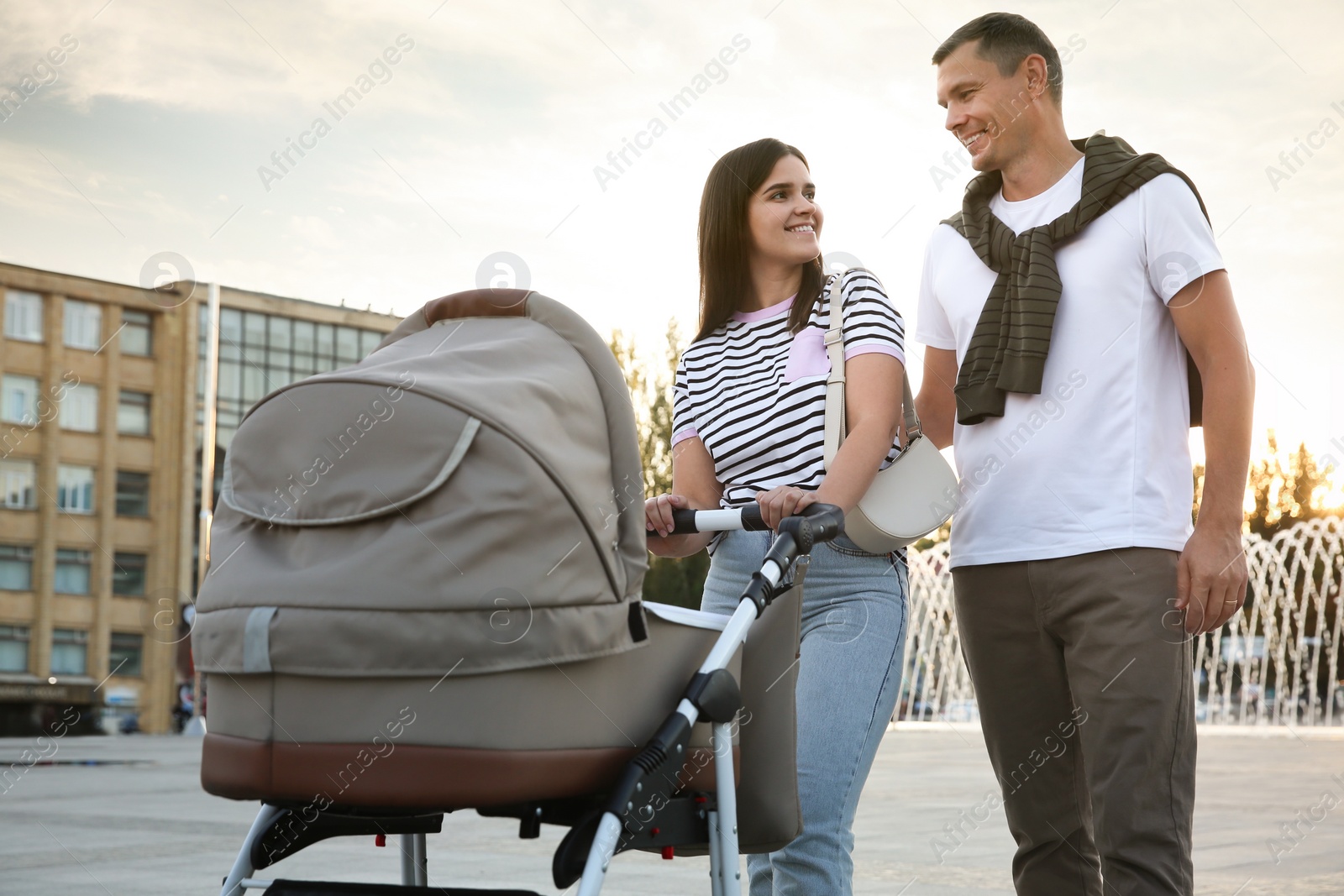 Photo of Happy parents walking with their baby in stroller outdoors