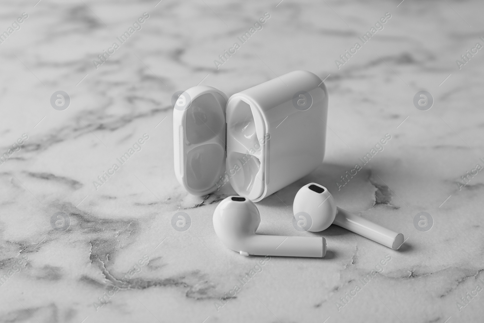 Photo of Charging case and wireless earphones on marble table