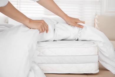 Photo of Woman putting blanket over soft white mattress on bed indoors, closeup