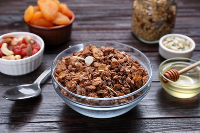 Photo of Tasty granola served with nuts, different ingredients on wooden table