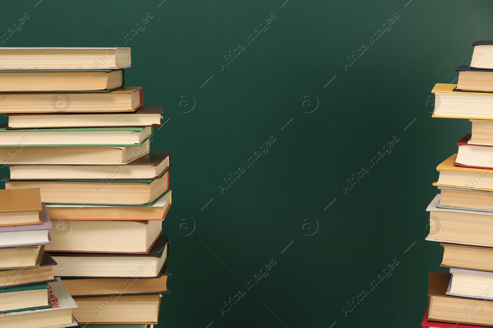 Photo of Many hardcover books near green chalkboard, space for text. Library material