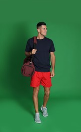 Photo of Handsome man with sports bag on green background