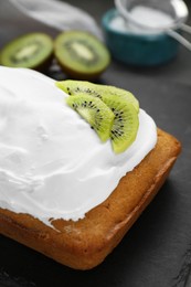 Photo of Delicious homemade yogurt cake with kiwi and cream on black table, closeup