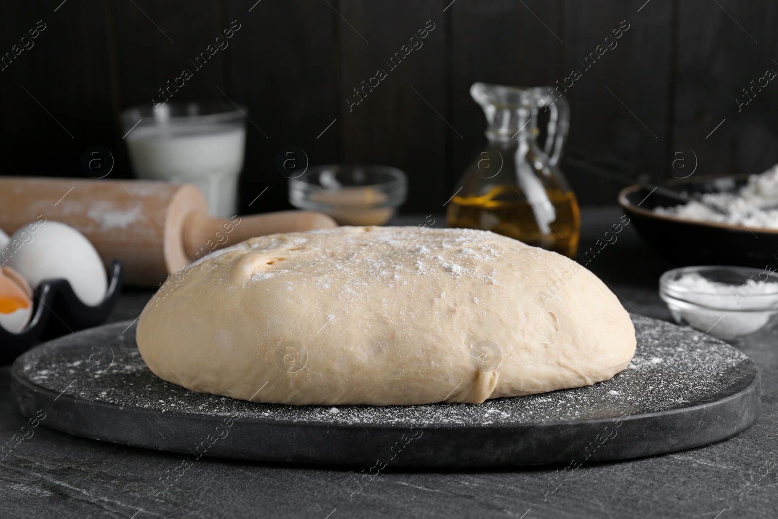 Photo of Fresh yeast dough with flour on black table